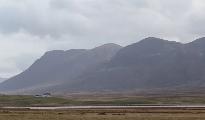Photo d'une ferme islandaise isolée au milieu d'une vallée entourée de 2 montagnes